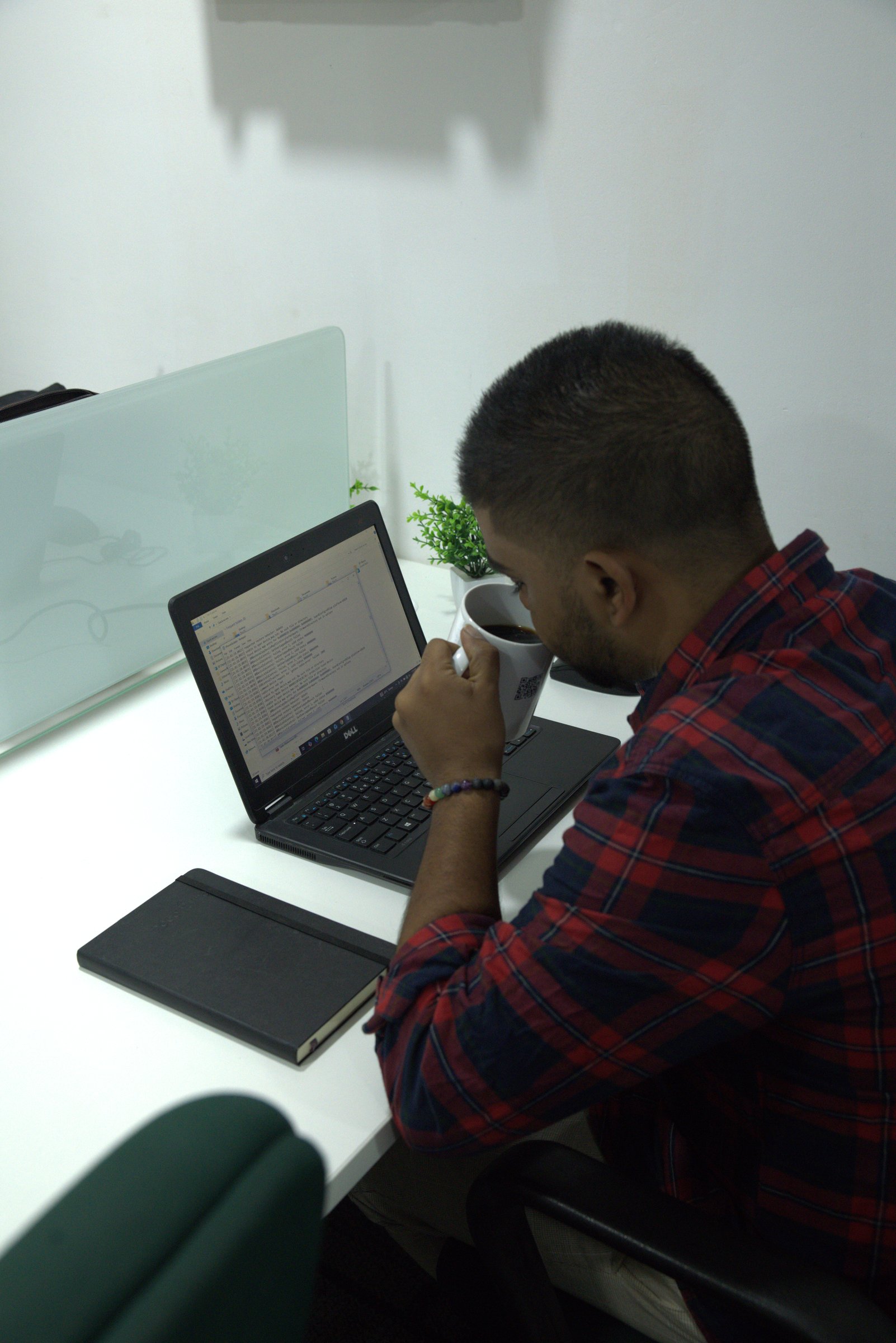Close-up of a workstation with laptop, notebook, charging points, comfortable chair, and coffee mug